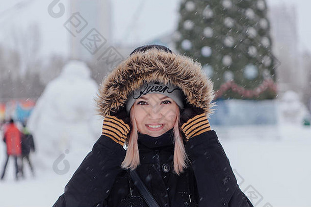 冬季时尚。一位穿着温暖衣服的美丽年轻女子在圣诞树旁的户外肖像