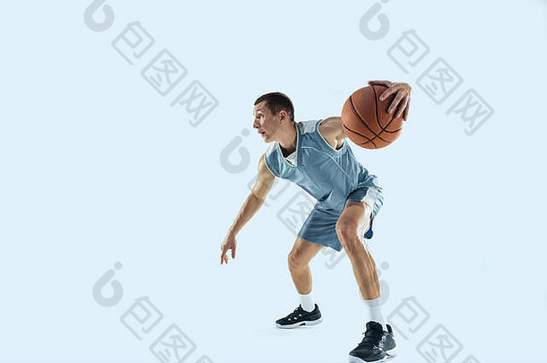 能量年轻的白种人篮球队员在比赛中，在蓝色背景上孤立地跳起。运动、运动、活力和健康生活方式的概念。训练，练习。