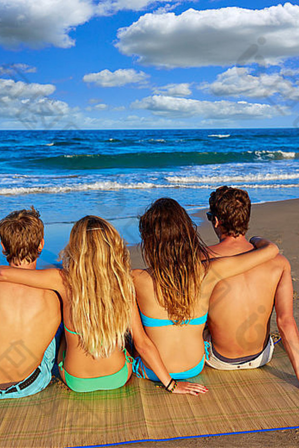 朋友团情侣们坐在沙滩上仰望大海