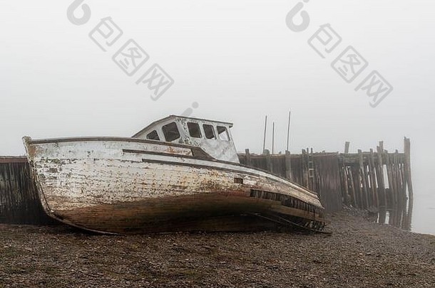 破坏了船海岸被遗弃的码头多雾的一天船可怜的形状下降低潮