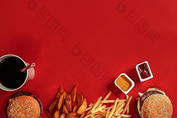 快餐盘俯视图。肉汉堡、薯片和一杯红色背景的饮料。外卖作文。