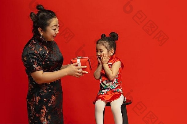 送礼物和幸福。2020年中国新年快乐。传统服装红色背景上的亚洲母女肖像。庆祝，人类情感，节日。空间。