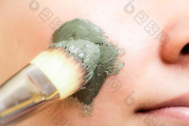 皮肤护理特写镜头女人应用刷粘土泥面具脸女孩采取护理干肤色美治疗