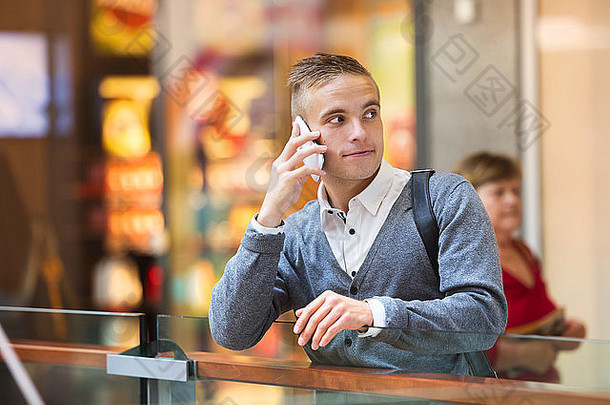 英俊的年轻的男人。购物购物中心移动电话