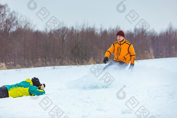 一名男子躺在地上给滑雪板运动员拍照