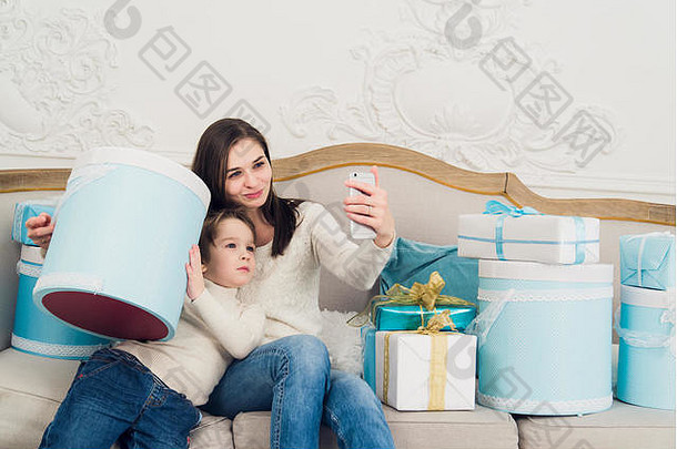 年轻的快乐家庭妈妈。儿子采取照片圣诞节礼物沙发生活房间