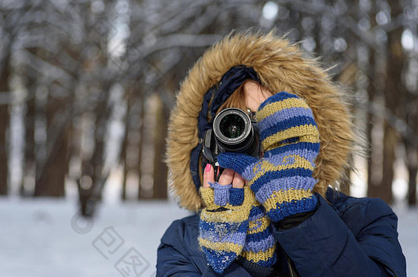 冬天，在森林里，一个穿着新鲜雪的女人用数码相机拍照