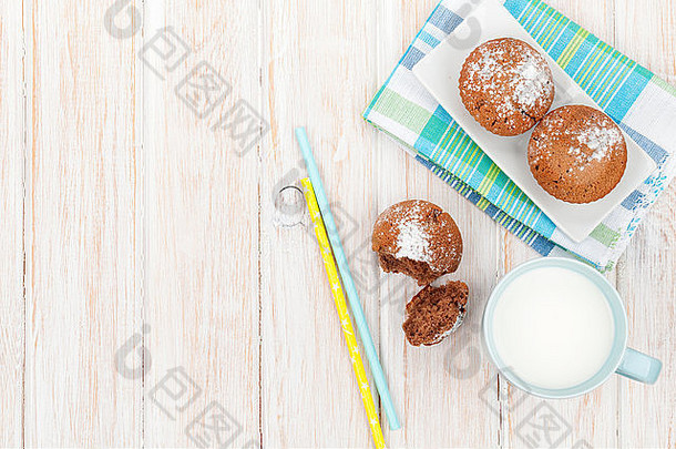一杯牛奶和蛋糕放在白色的木桌上。具有空间的俯视图