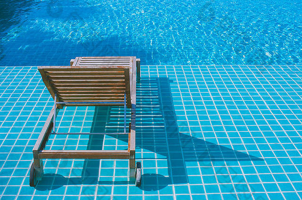 <strong>放</strong>松概念：度假区游泳池马赛克<strong>瓷砖上</strong>的木制床。