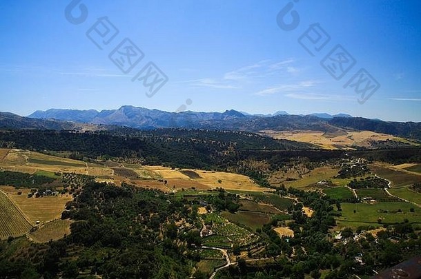 从西班牙安达卢西亚的隆达古村落俯瞰广阔的乡村山谷，与万里无云的蓝天形成对比