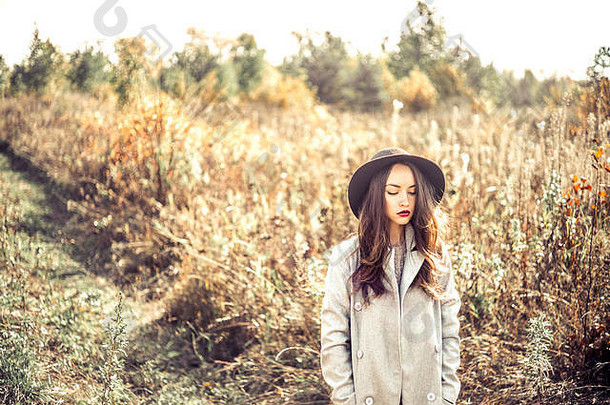 户外时尚照片，年轻美丽的女士在秋天的风景与干花。灰色的外套，黑色的帽子，葡萄酒口红。温<strong>暖</strong>的秋天。<strong>暖春</strong>