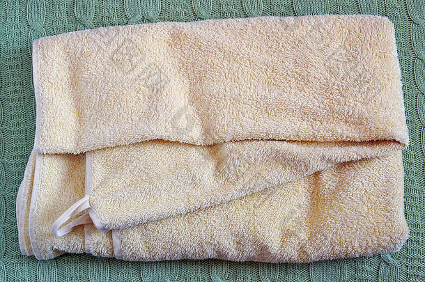 毛圈布黄色干洗浴巾躺在羊毛针织床罩上