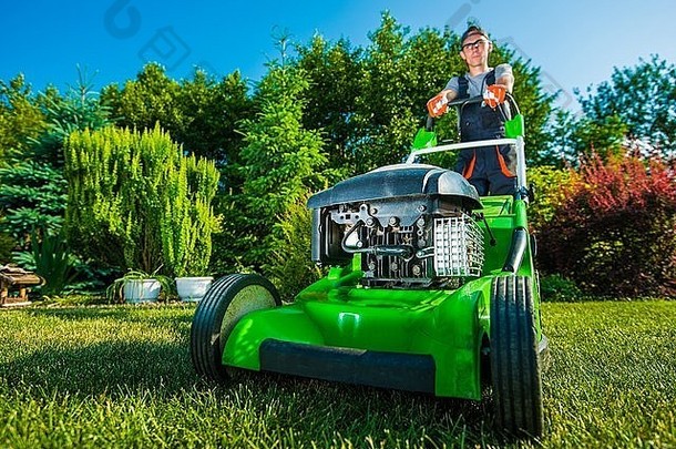 景观业务园丁割草后院草坪上绿色汽油草坪上割草机
