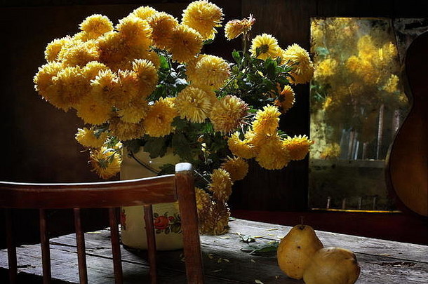 木桌上摆着黄色花朵和梨子的静物画