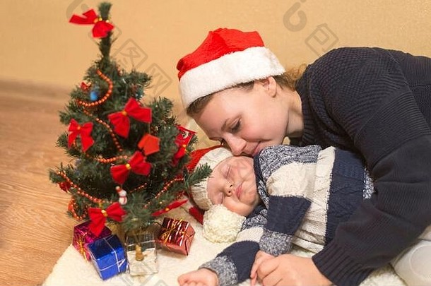 妈妈戴着圣诞老人的帽子拥抱熟睡的婴儿