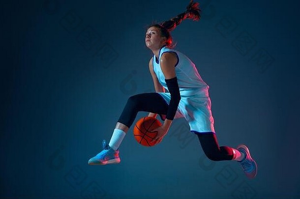飞行年轻的高加索人女篮球球员蓝色的工作室背景霓虹灯光运动行动概念体育运动运动能源动态健康的生活方式培训练习
