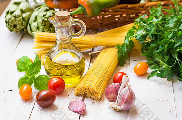 意大利和地中海美食配料，意大利面条，橄榄油，大蒜，西红柿，朝鲜蓟，甜椒，放在厨房桌子上的篮子里，户外，