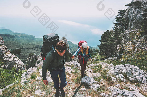 情侣们手牵手在山上远足，爱和旅行的生活方式理念。背包客家庭一起旅行积极冒险度假
