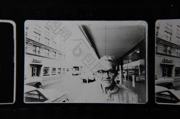 精美的70年代复古隐形印花黑白极限摄影作品，拍摄一名男子站在一条商业大道上，