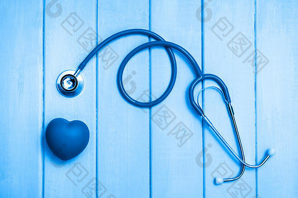 木制背景上的听诊器和心脏。蓝色吨。
