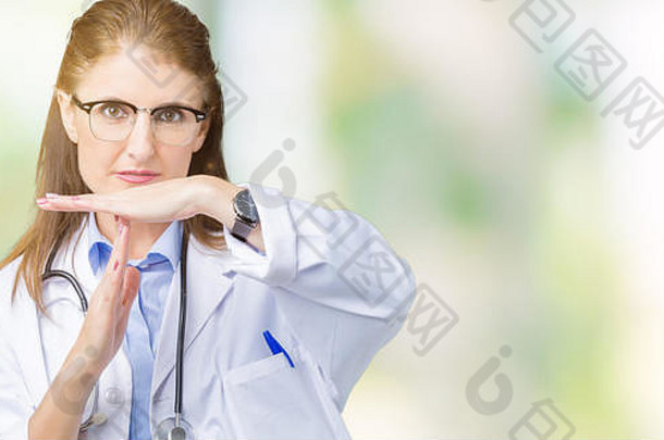中年成熟的女医生穿着医用外套在孤立的背景下做超时手势，脸上沮丧而严肃