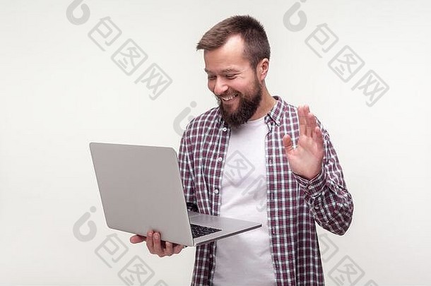 这就跟你问声好！肖像积极的有胡子的男人。休闲格子衬衫挥舞着手移动PC使视频调用在线会说话的社会网络快乐微笑