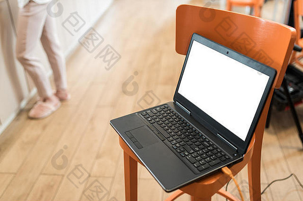 放在橙色椅子上的带夹式显示屏的笔记本，配备硬件设备的工作场所