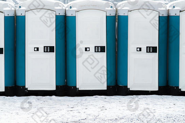外面雪地上有一排长长的移动厕所。户外生物厕所