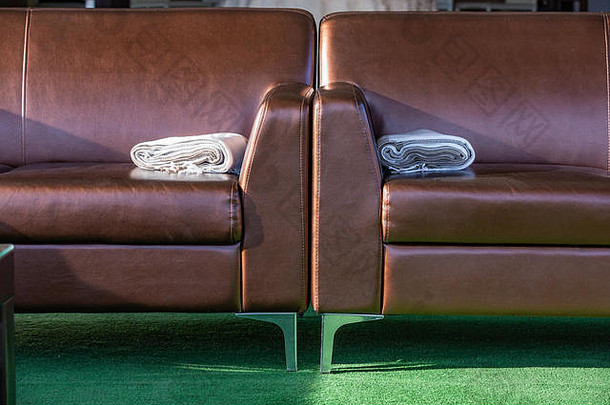 特写现代优雅的棕色皮革休闲沙发，扶手上有羊毛地毯。
