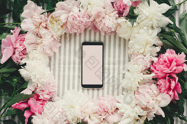 手机的屏幕是空的，桌面上有粉色和白色的牡丹花架，平板上有文字空间。母亲节快乐。国际妇女节。招呼