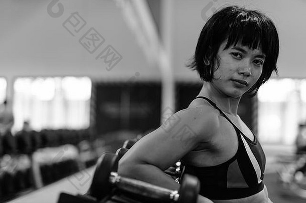 年轻漂亮的亚洲女人穿着黑白相间的衣服在健身房锻炼