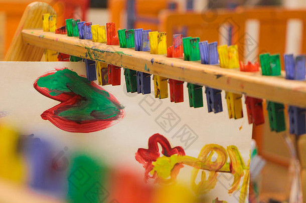 明亮的幼儿园孩子们在教室里把画挂在钉子上晾干。
