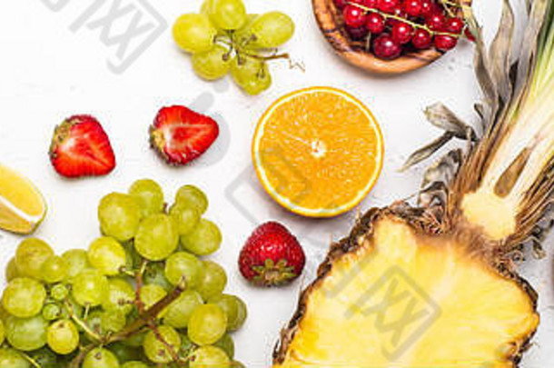 白色餐桌上的热带水果和浆果。菠萝、葡萄、柑橘和浆果的混合物。