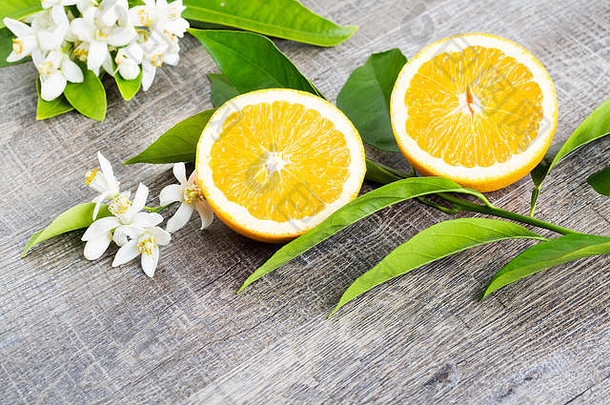 多汁的橙子切成两部分，橙花，橘子树的花朵，在乡村木背景上。橘子花是柑橘属植物的芳香之花