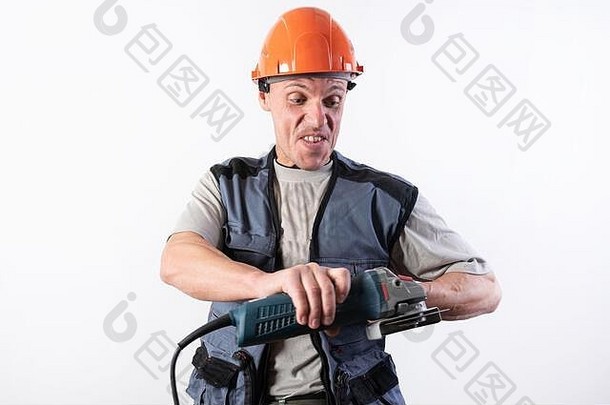 建筑工人戴着角磨机，戴着头盔，脸上带着滑稽的表情。