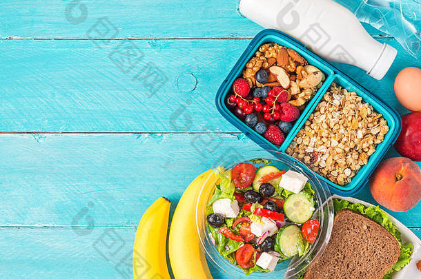 集健康的午餐盒子希腊沙拉三明治格兰诺拉麦片蔬菜坚果浆果香蕉鸡蛋桃子<strong>酸奶</strong>蓝色的背景前