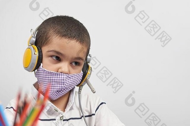 戴着耳机的小孩通过笔记本电脑做在线练习。在线或远程学习<strong>外语</strong>，电子学习概念