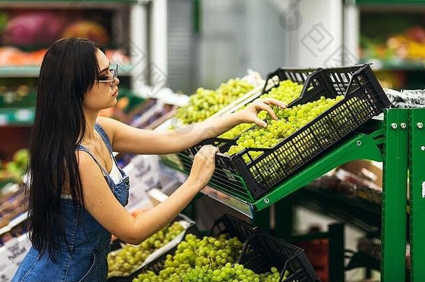 购物者女孩选择葡萄超市