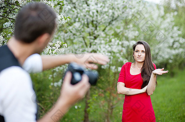 摄影师正在拍摄大自然中穿着红色衣服的美丽女子
