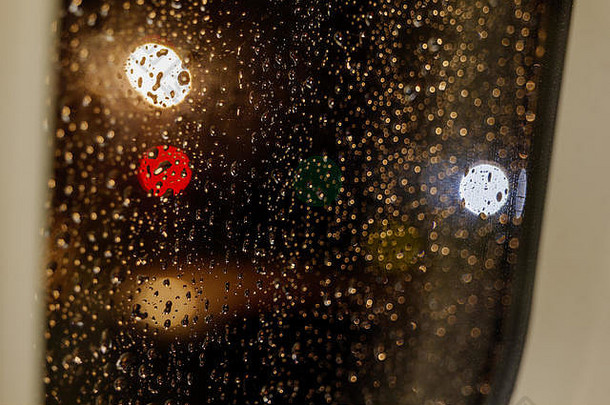 飞机内窗窗框玻璃上滴下水滴，背景用红、金、黄三种颜色的圆形灯光模糊