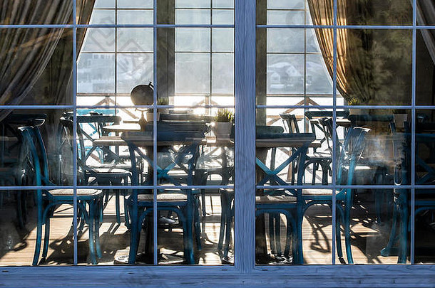 日落时阳光反射下的玻璃幕墙后面的夏季咖啡馆内部