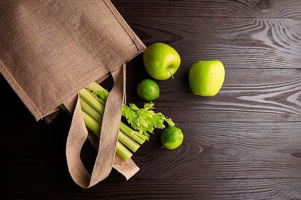 可重用的购物袋新鲜的水果绿色木背景前视图黄麻袋自然<strong>环保材料</strong>绿色苹果酸橙这