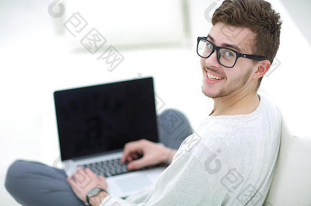 年轻人在明亮的客厅里使用笔记本电脑的后视图