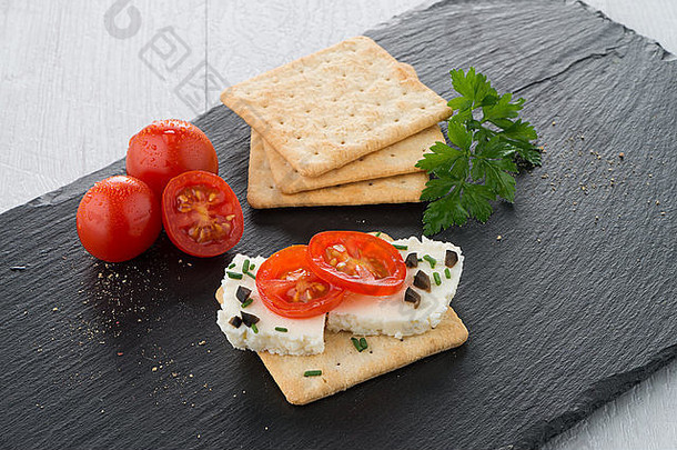 黑橄榄色托盘上的薯<strong>片</strong>面包配fromage、西红柿和橄榄。