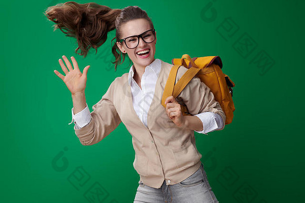 微笑年轻的学生女人跳挥臂孤立的绿色背景