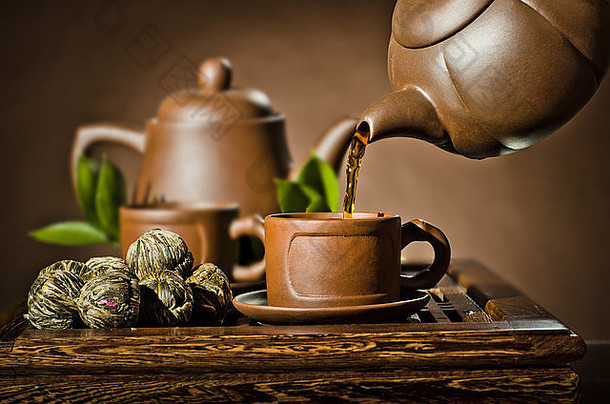 水平照片，茶壶茶水在茶杯中流动的棕色背景，茶道