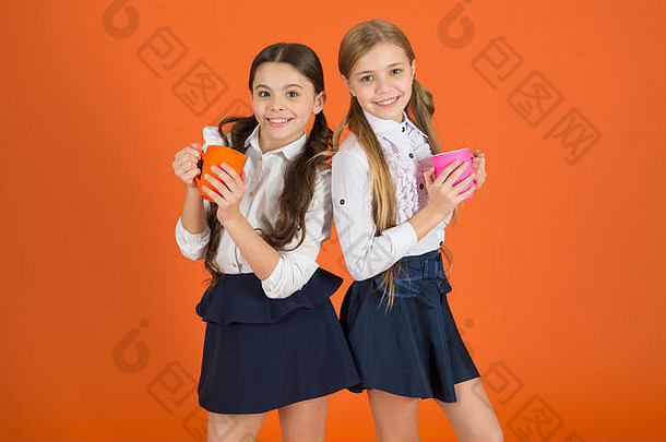 女孩孩子们学校统一的橙色背景女学生持有杯子学校午餐打破放松喝茶打破学校伴侣放松喝水合作用水政权茶打破