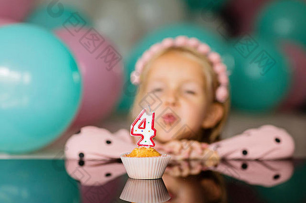 室内拍摄的美丽快乐的金发小女孩吹灭蜡烛，庆祝4岁生日，穿着时装，兴奋不已