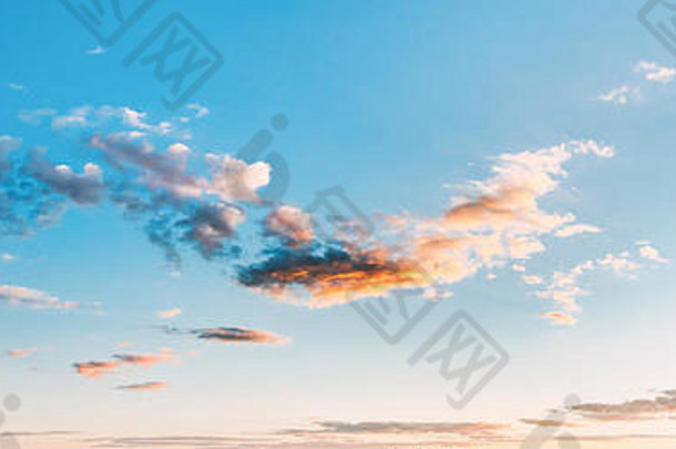 明亮的蓝天和蓬松的白云的全景。日落或日出背景下的蓝色阳光云景