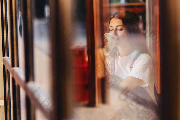 年轻的有吸引力的漂亮的女孩咖啡馆咖啡放松早....throuth窗口玻璃